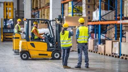 Warehouse workers with hard hats and a forklift